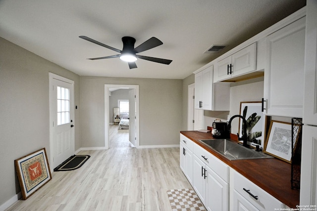 kitchen with butcher block counters, sink, and white cabinets