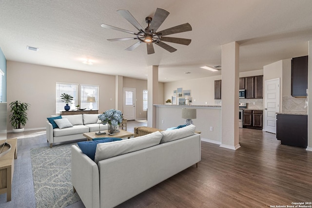 living room with a textured ceiling, dark hardwood / wood-style floors, and ceiling fan