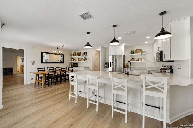 kitchen featuring a kitchen bar, sink, white cabinets, and appliances with stainless steel finishes