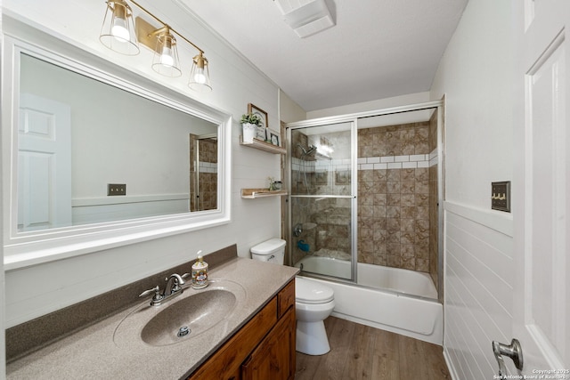 full bathroom featuring bath / shower combo with glass door, wood-type flooring, vanity, and toilet