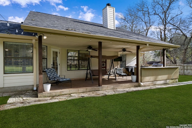 back of property with ceiling fan, a patio, and a lawn