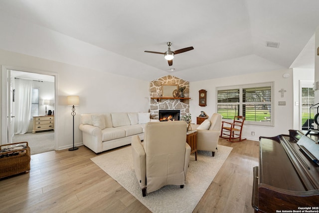 living room featuring ceiling fan, lofted ceiling, a fireplace, and light hardwood / wood-style flooring