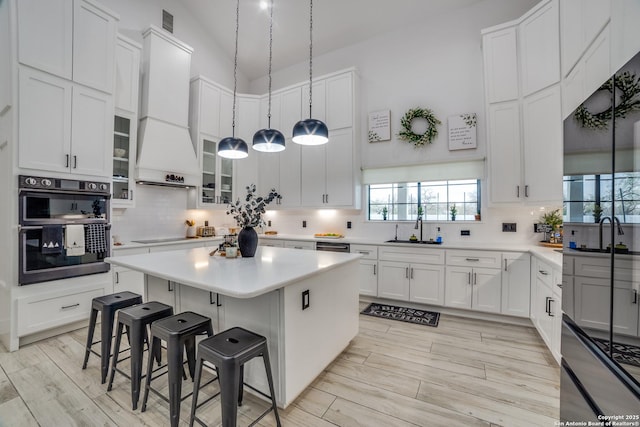 kitchen featuring white cabinetry, double oven, hanging light fixtures, and a kitchen island