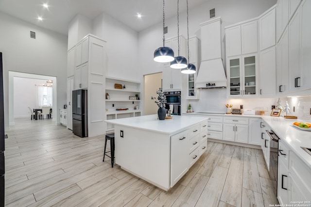 kitchen with black appliances, a center island, white cabinets, and a high ceiling