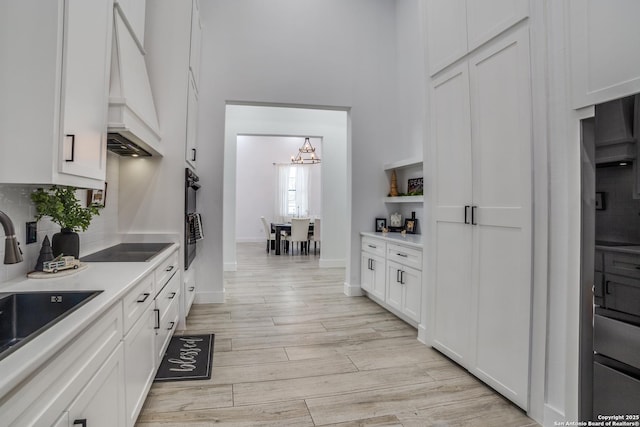 kitchen featuring white cabinetry, sink, custom exhaust hood, and black appliances