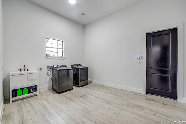 washroom featuring sink, washer and dryer, and light hardwood / wood-style flooring