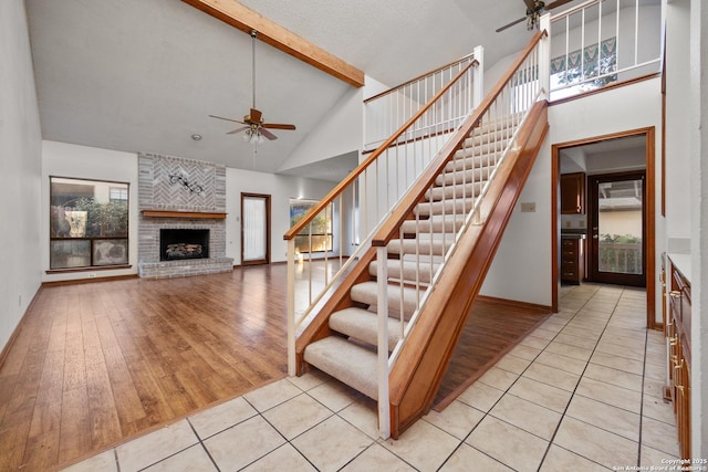 stairs with ceiling fan, high vaulted ceiling, tile patterned flooring, and a wealth of natural light