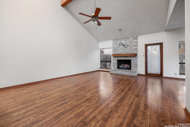 unfurnished living room with dark wood-type flooring, a fireplace, high vaulted ceiling, and ceiling fan