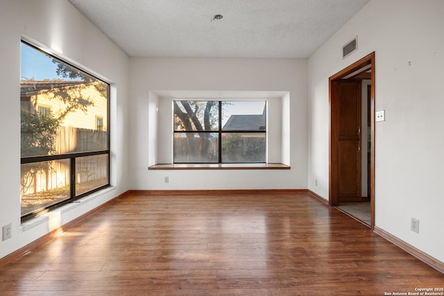 unfurnished room featuring dark wood-type flooring and a textured ceiling