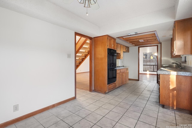 kitchen with double oven, sink, and light tile patterned flooring