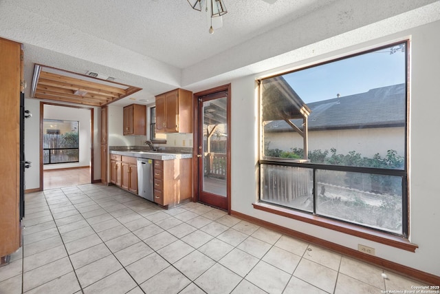 kitchen with light tile patterned flooring, sink, a textured ceiling, dishwasher, and a raised ceiling