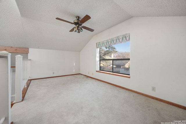 additional living space with ceiling fan, vaulted ceiling, light carpet, and a textured ceiling