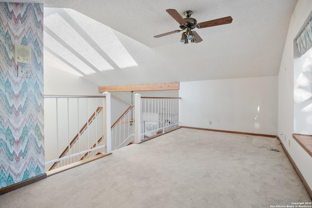 additional living space featuring ceiling fan, vaulted ceiling with skylight, light carpet, and a textured ceiling