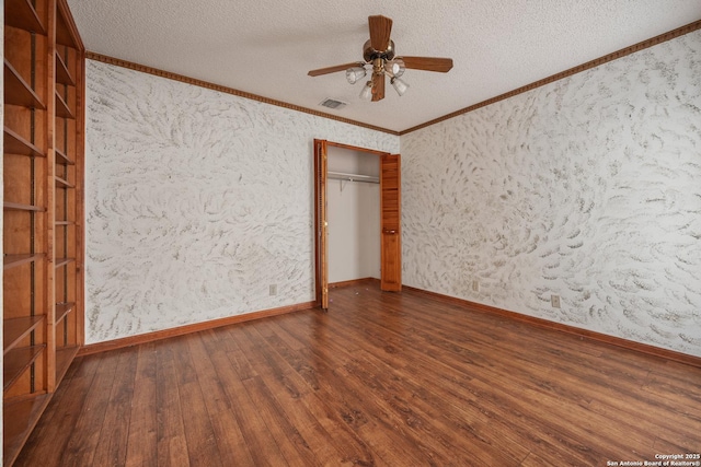 unfurnished bedroom with dark wood-type flooring, ceiling fan, ornamental molding, a textured ceiling, and a closet