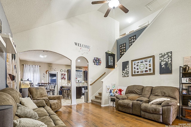 living room with hardwood / wood-style flooring, vaulted ceiling, ceiling fan, and a textured ceiling