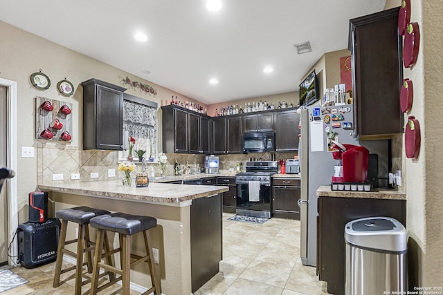 kitchen with light tile patterned flooring, gas stove, a kitchen breakfast bar, kitchen peninsula, and decorative backsplash