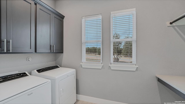 clothes washing area with cabinets and washer and dryer