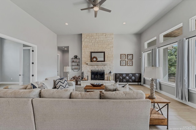 living room featuring ceiling fan, a fireplace, and light wood-type flooring