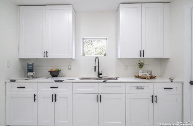 bar with white cabinetry and sink