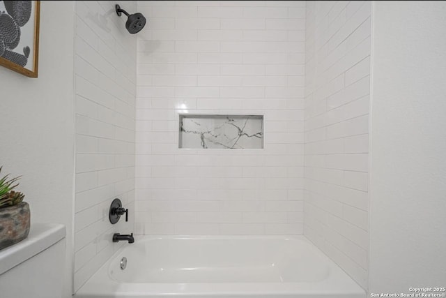 bathroom featuring tiled shower / bath and toilet