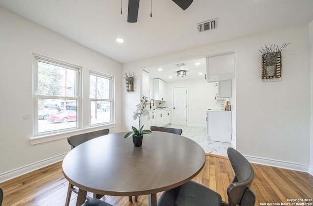 dining space with ceiling fan, sink, and light hardwood / wood-style floors