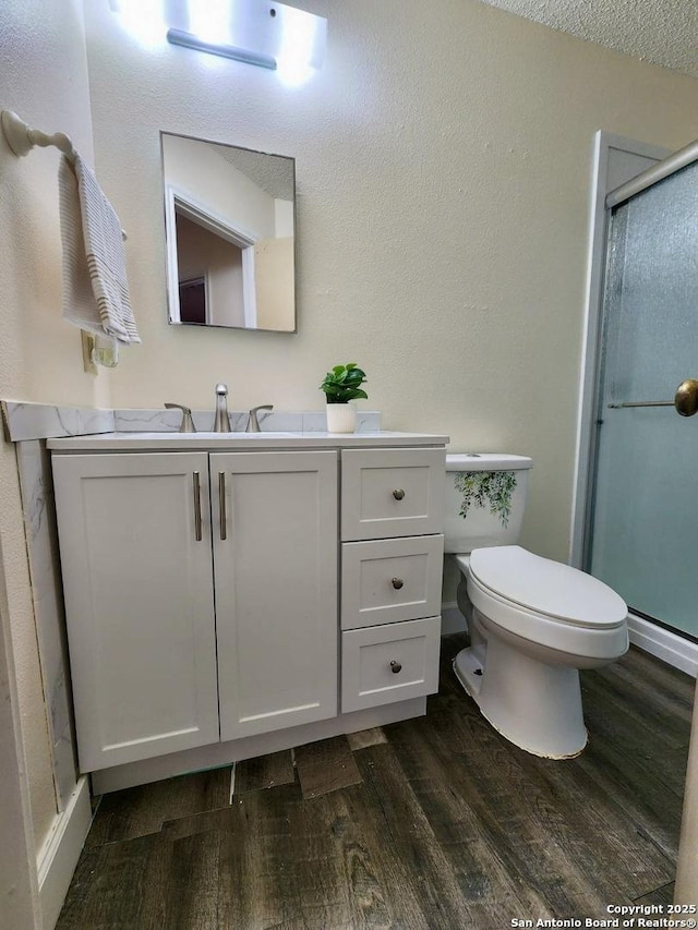 bathroom with vanity, hardwood / wood-style floors, a shower with door, and toilet