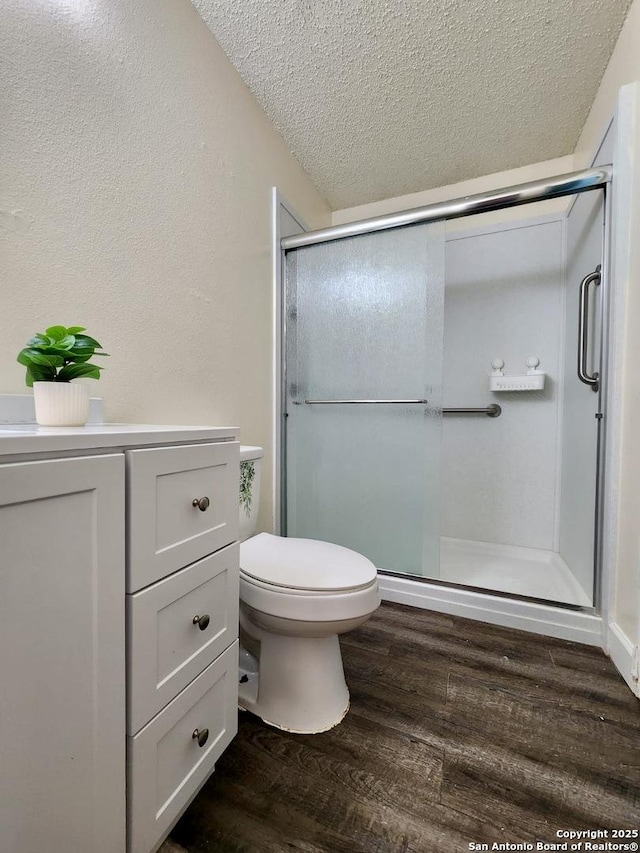 bathroom with wood-type flooring, walk in shower, a textured ceiling, and toilet