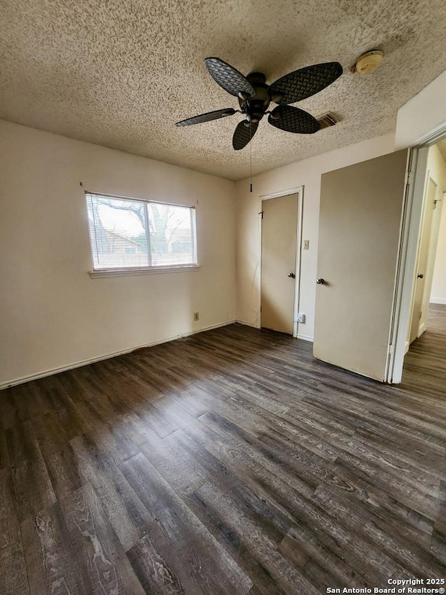 unfurnished bedroom with a textured ceiling, dark wood-type flooring, and ceiling fan