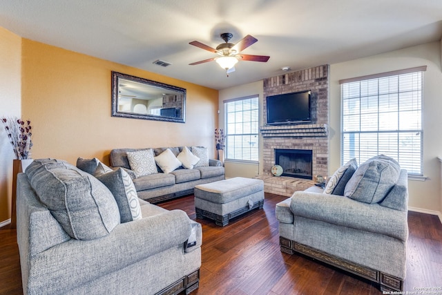 living room with a brick fireplace, dark hardwood / wood-style floors, and ceiling fan