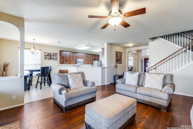 living room with ceiling fan with notable chandelier and dark wood-type flooring