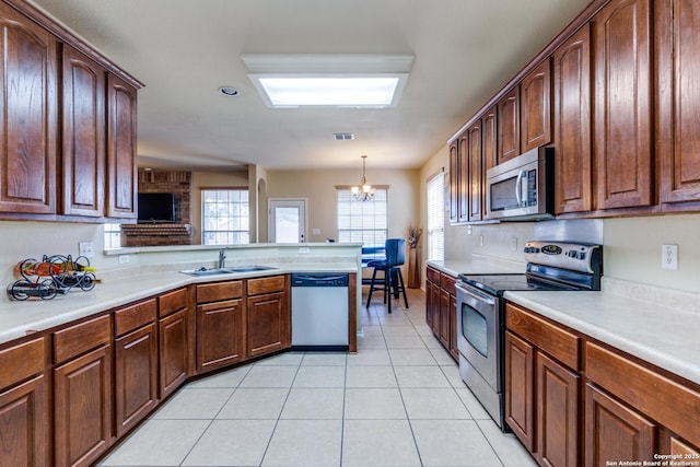 kitchen featuring pendant lighting, sink, light tile patterned floors, stainless steel appliances, and an inviting chandelier