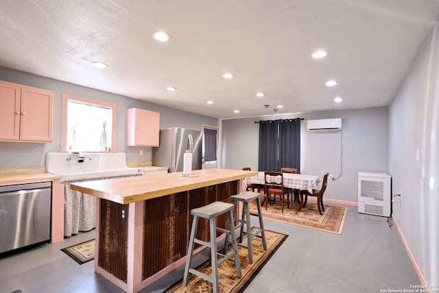 kitchen with a breakfast bar, butcher block countertops, a wall mounted air conditioner, appliances with stainless steel finishes, and a kitchen island