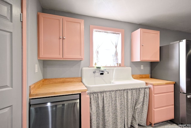 kitchen featuring appliances with stainless steel finishes, butcher block counters, sink, and light brown cabinets