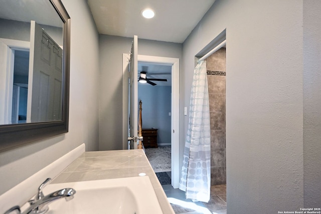 bathroom featuring ceiling fan, curtained shower, and sink