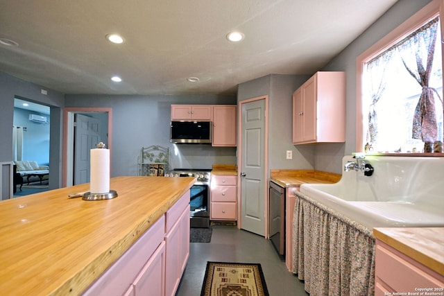 kitchen with concrete flooring, appliances with stainless steel finishes, wooden counters, and light brown cabinetry