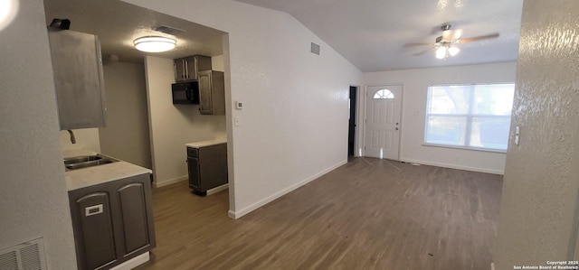 kitchen with dark wood-type flooring, sink, vaulted ceiling, dark brown cabinets, and ceiling fan