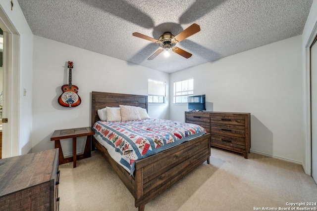 carpeted bedroom featuring ceiling fan and a textured ceiling