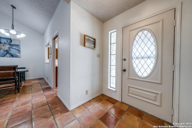 tiled entrance foyer featuring lofted ceiling, a healthy amount of sunlight, an inviting chandelier, and a textured ceiling