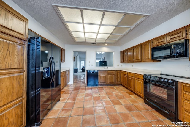 kitchen with light tile patterned floors, a textured ceiling, and black appliances