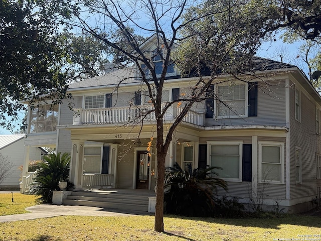 view of front of home featuring a balcony and a front yard