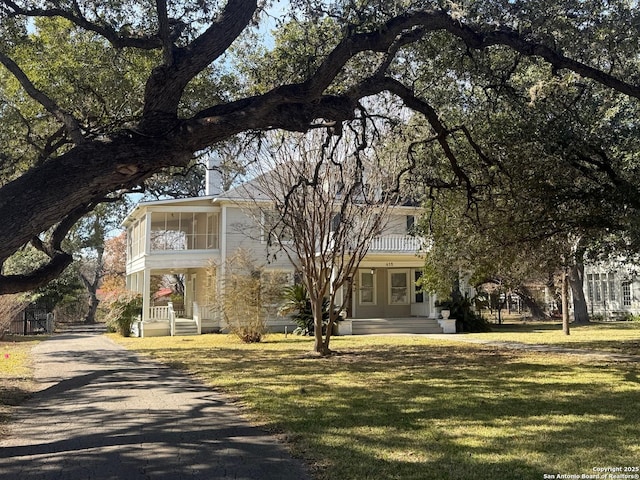 view of front of home with a sunroom and a front yard