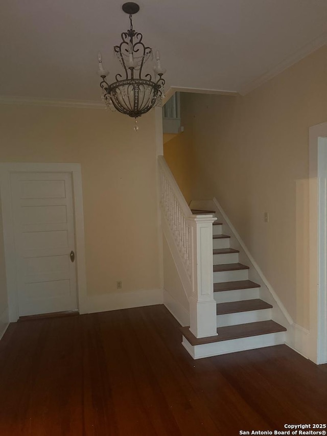 staircase featuring hardwood / wood-style flooring, ornamental molding, and a notable chandelier