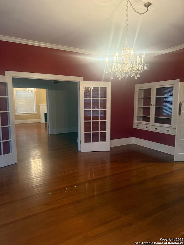 spare room with an inviting chandelier, hardwood / wood-style floors, and ornamental molding