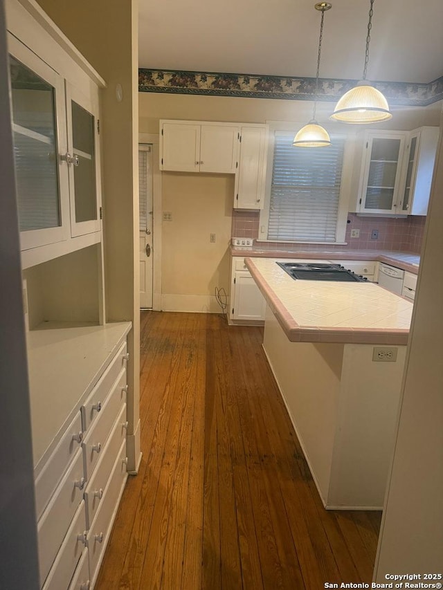 kitchen with tasteful backsplash, black stovetop, white cabinets, dark hardwood / wood-style flooring, and decorative light fixtures