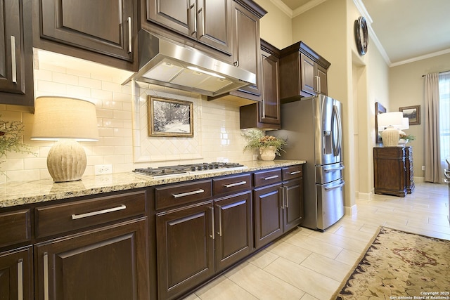 kitchen with appliances with stainless steel finishes, backsplash, light stone counters, dark brown cabinetry, and crown molding