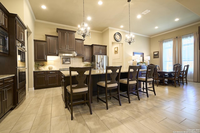 kitchen featuring stainless steel appliances, a breakfast bar, a kitchen island with sink, and hanging light fixtures