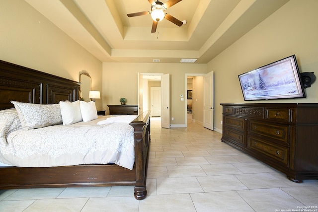 bedroom featuring a raised ceiling, ceiling fan, and light tile patterned flooring