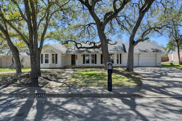 ranch-style home featuring a garage, brick siding, fence, and driveway