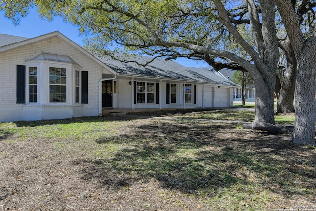 view of front facade featuring an attached garage, a front lawn, and brick siding