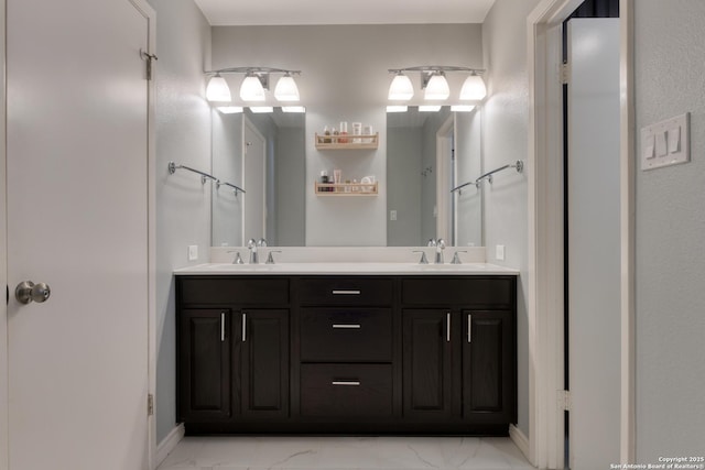 bathroom with marble finish floor, a sink, and double vanity